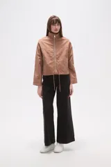 Campera de corte holgado en color tostado, confeccionada en poliamida. Presenta cuello alto, cierre frontal con cremallera, bolsillos laterales con cierre y cordón ajustable en el ruedo.