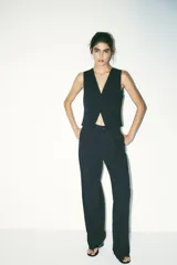 Pantalón de tiro alto color negro, confeccionado en hilatura con 22% de lino. Presenta bolsillos delanteros, detalle de pliegues, y cierre frontal con cremallera y botón.