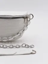 Riñonera blanca con textura símil cuero de cocodrilo, con bolsillo pequeño extraíble con cierre y correa ajustable.