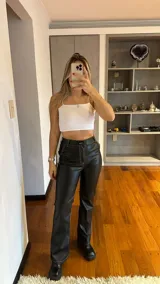 Pantalón de cuerina negro, tiro alto y acampanado, con costuras blancas a la vista.