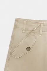 Pantalón cargo color beige de la colección Zara Woman, con tiro medio, cintura con trabillas, bolsillos delanteros y de plastrón con solapa en la pierna. Cierre frontal con cremallera y botón.