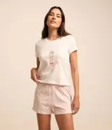 Pijama de dos piezas, compuesto por una remera blanca de manga corta con estampa de surf y un short rosa con lunares negros y cintura elástica.