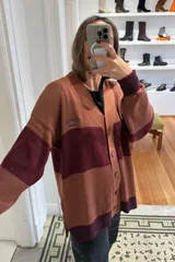 Cárdigan oversized negro con bloques de color rojo en mangas y frente, logo bordado en el pecho y logo texturizado en la espalda.