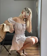 Vestido corto blanco con escote off-shoulder, mangas cortas abullonadas y cintura elastizada.