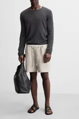 Bermuda regular fit negra confeccionada en tejido de lino. Cintura elástica ajustable con cordón y pliegues frontales. Bolsillos frontales y detalle de bolsillos traseros de plastrón.