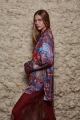 Camisa holgada estampada con motivos geométricos en tonos azul, rojo y marrón. Tiene cuello solapa, mangas largas y cierre abotonado.