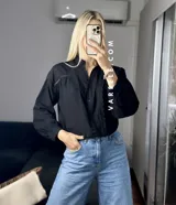 Camisa blanca de mangas largas con puños abullonados y detalles de encaje en cuello, mangas y ruedo.