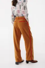 Pantalón de vestir color marrón con corte recto y cintura alta. Presenta una fina cinta roja a modo de cinturón.
