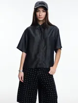 Camisa negra de manga corta confeccionada en denim liviano de tencel, de calce cuadrado y relajado. Presenta cierre frontal con tapeta escondida y costuras en color contraste.