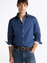Camisa azul de popelín de algodón con tecnología Flex, cuello abotonado, puños redondeados con botón, logo de Tommy Hilfiger bordado en el pecho y corte regular.