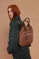 Mochila color vainilla con detalles en cuero marrón, diseño moderno y funcional. Cuenta con un amplio compartimento principal, un bolsillo frontal con cierre y dos asas superiores. Incluye correas ajustables para llevarla como mochila.