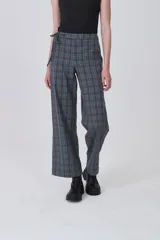Pantalón de poliéster con estampado tartán en tonos grises y azules. Diseño de tiro medio, corte recto y ancho, con detalle de lazo ajustable en la cintura.