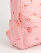 Mochila rosa con estampado de cerezas, correas regulables, manija superior, doble cierre superior y bolsillo frontal con cierre.
