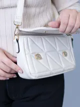 Bandolera color blanco con diseño capitoneado, correa larga regulable y cierre con solapa.