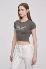 Remera gris de corte crop con cuello redondo y mangas cortas. Estampado frontal con alas y texto "Angel on Earth".