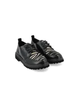 Zapato acordonado de cuero negro con suela track y detalle de pespuntes en color crudo.