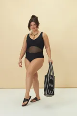 Malla enteriza negra con escote cruzado, breteles anchos y panel de tul transparente en la zona del abdomen.