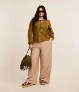 Pantalón de corte ancho confeccionado en sastrería de viscosa color beige, con cintura alta, trabillas, cierre con botón forrado y bolsillos laterales.