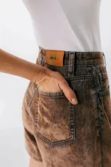 Short de jean color marrón con efecto desgastado, tiro alto y corte holgado.