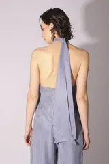 Conjunto de blusa y pantalón color gris azulado de seda, con cuello halter y corte holgado.