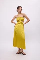 Vestido midi amarillo de satén con escote halter, trenzas en cuello y cintura, cut-outs laterales y falda recta.