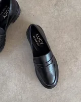 Mocasines negros con suela track y detalle de antifaz con textura croco.