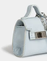 Monedero de cuerina celeste con forma de bolso pequeño, manija superior, solapa con broche de botón y mosquetón lateral con cadena plateada.