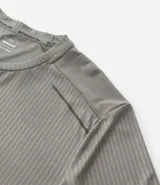 Remera deportiva de manga corta y cuello redondo, color beige claro, con textura acanalada vertical. Presenta detalles reflectantes en los hombros.