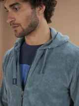 Campera con capucha de toalla de algodón color verde azulado, con cierre frontal y bolsillos laterales.