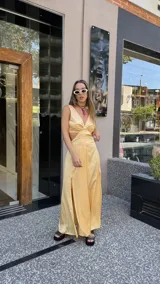 Vestido largo color durazno con escote pronunciado en V y aberturas laterales en la cintura. Presenta un drapeado frontal y falda con tajo lateral.