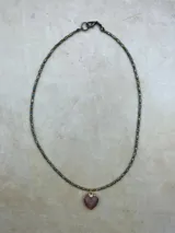 Collar de múltiples hebras con cuentas pequeñas de tonos tierra, rojo y azul, y dijes colgantes en forma de corazón con piedras semipreciosas engarzadas en metal dorado.