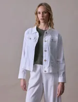 Campera de lino color blanco, marca Dash. Tiene abertura central con botones, bolsillos aplicados en el frente y composición de 55% lino y 45% rayón.