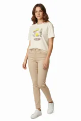 Remera de manga corta color crema con estampado de limones, flores y utensilios de cocina. Cuello redondo.