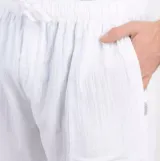 Pantalón de lino blanco, de corte recto y tiro medio, con cintura elástica ajustable con cordón y bolsillos laterales.
