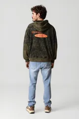 Canguro oversize con capucha, color verde militar con efecto tie-dye en negro y estampado con la palabra "Reason" en el pecho.
