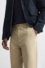 Pantalón color arena de corte recto, confeccionado en tejido de algodón con estructura canvas. Cuenta con cintura ajustable con trabillas laterales, bolsillos frontales y traseros de vivo. Cierre frontal con cremallera y botón.