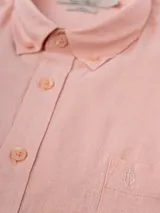 Camisa de manga larga azul, de lino y poliéster, con cuello abotonado y bolsillo en el pecho.