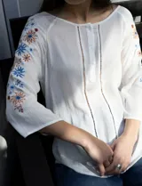 Blusa azul con escote redondo, mangas 3/4 con bordado floral y abertura central con botones. Marca Forgotten Grace.