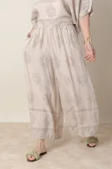 Pantalón palazzo de lino color crudo con estampado floral al tono, tiro alto y cintura elastizada.