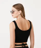 Top cropped sin mangas, color negro, con escote cuadrado y abertura frontal con broches. Presenta textura acanalada.