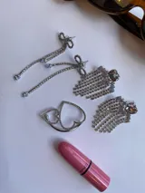 Par de aros colgantes con forma de corazón de cristal y flecos de strass plateados.