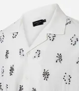Camisa de manga corta para hombre, corte boxy, color blanco con cuello bowling y un estampado repetitivo de figuras geométricas negras.