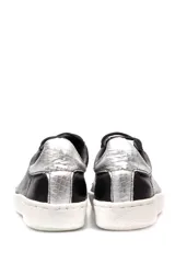 Zapatillas bajas negras de cuero liso, con cordones y suela blanca.