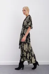 Vestido largo negro con estampado floral dorado en lurex, escote en V cruzado, mangas al codo, cintura elastizada con lazo y viso al tono con breteles regulables y puntilla en el escote.