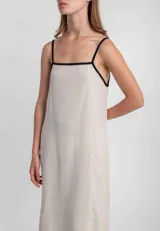 Vestido largo verde oliva de lino, con breteles finos negros y escote cuadrado con ribete negro.