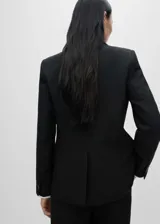 Blazer negro de corte recto con cuello de pico con solapa, tres bolsillos de solapa en la parte frontal y manga larga con puños abotonados.