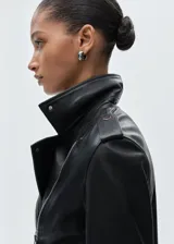 Chaqueta de cuero ovino negra, corte slim, con cuello con solapa, cierre frontal asimétrico con cremallera, mangas largas con cremallera en los puños y dos bolsillos laterales con cremallera.