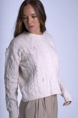 Sweater color crema de punto con diseño de ochos y flores bordadas. De corte holgado y mangas largas.