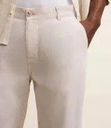 Pantalón de lino blanco de corte recto, con trabillas en la cintura, cierre tradicional y bolsillos laterales.