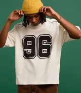 Remera de corte boxy color crema con estampa del número 96 en el frente y detalles en negro en cuello y mangas.